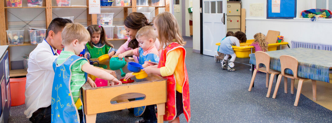 A photograph of a group of children in a kindergarten classroom with their teacher.